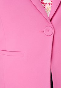 Roze blazer met een gladde textuur, enkele knoopsluiting en een notch-kraag. Beschikt over een verborgen zakdetail en een bloempatronenvoering.