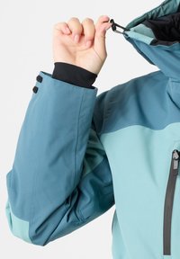 Jacket in shades of teal with a high collar, zippered pocket, and adjustable drawstring. Features a black inner cuff for added protection.