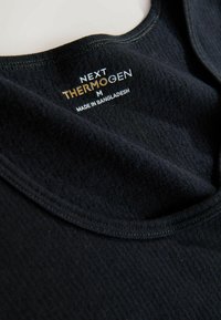 Maglia termica nera con una texture liscia e una scollatura arrotondata. L'etichetta riporta "NEXT THERMOGEN M, MADE IN BANGLADESH."
