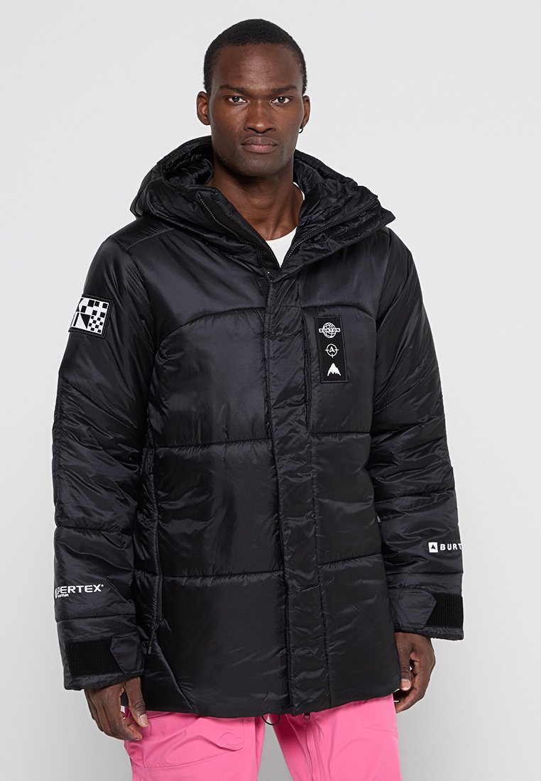 Schwarze Pufferjacke mit Kapuze, ausgestattet mit Marken-Patches, einem gesteppten Design und gerippten Bündchen. Leichtes, isolierendes Außenmaterial.