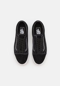 Baskets en daim noir avec coutures blanches, lacets plats et semelle extérieure en caoutchouc. Dotées d'un design classique à tige basse et du logo Vans sur la languette.