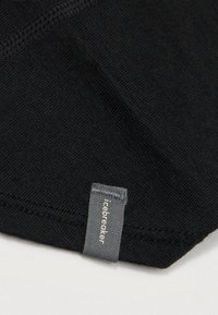 Μαύρο ύφασμα με λεία υφή, που διαθέτει μια μικρή γκρι ετικέτα με την ένδειξη "icebreaker" στην άκρη. Τελειωμένες άκρες με διακριτική ραφή.