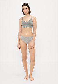 Pelēka bralette ar regulējamām siksnām un "POLO" tekstu, apvienota ar atbilstošām pelēkām hipster biksītēm, kurām sānos ir mazs logo.