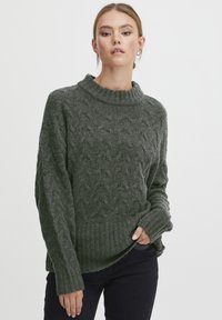 Dunkelgrüner Strickpullover mit hohem, geripptem Kragen und strukturiertem Muster. Verfügt über lange Ärmel und einen gerippten Saum für zusätzlichen Details.