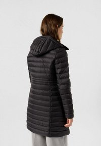 Abrigo de plumas negro con capucha, que presenta acolchado horizontal y un diseño entallado que se ajusta a la cintura, fabricado en un material suave y ligero.