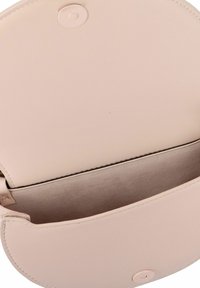 Bolso de mano redondo de cuero de color rosa claro con una textura suave y cierre a presión. El interior muestra un forro suave, sin compartimentos adicionales.