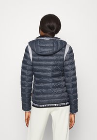 Dunkelblaues Puffer-Jackett mit Kapuze, mit gestepptem Design, gerippten Bündchen und einem schwarz-weißen Logo-Gummibund.