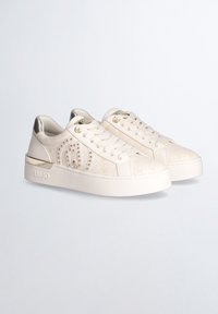 Hvide sneakers med et tekstureret mønster, guld accenter og et glat materiale. Har en polstret ankel og en tykk gummisål.