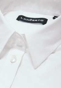 Biała bawełniana koszula z kołnierzykiem typu wskazującego, z przezroczystymi guzikami i czarną metką z napisem "LANCERTO". Gładka faktura i prosty design.