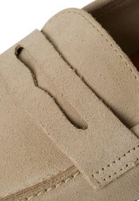 Beige nubuk cipele s izrazitim izrezanim dizajnom, šivenim rubovima i glatkom, mekanom teksturom. Donji deo cipele nije vidljiv.