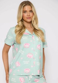 Mintgroen pyjama set met korte mouwen en knopen, met bedrukte roze theekopjes en tekstopdruk. Zachte stof met een gladde textuur.