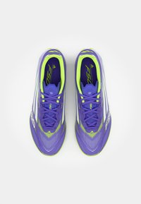 Scarpe da calcio viola con accenti verdi, caratterizzate da un design testurizzato, una forma slanciata e strisce riflettenti sulla parte superiore.