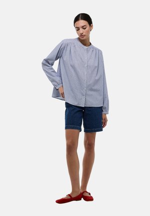 Chemise à carreaux bleus et blancs à manches longues et col rond, associée à un short en denim et des ballerines rouges.