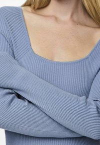 Pull côtelé bleu clair avec un col carré et des manches longues, doté d'une texture douce et d'une coupe près du corps.