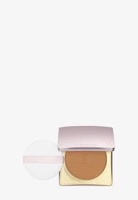 Kompaktowy puder w jasnoróżowym metalicznym etui, złote wnętrze i gładki brązowy puder. Zawiera biały aplikator z różową opaską.