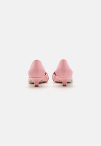 Różowe skórzane buty na obcasie z zaokrąglonym noskiem i niskim obcasem typu kitten heel. Gładka faktura z błyszczącym wykończeniem. Otwarty bok dla wentylacji.