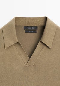 Oliwkowa bawełniana koszulka polo z dekoltem w serek, płaskim kołnierzykiem oraz fakturowanym materiałem. Metka wskazuje "Massimo Dutti" i informuje o 100% bawełnie.