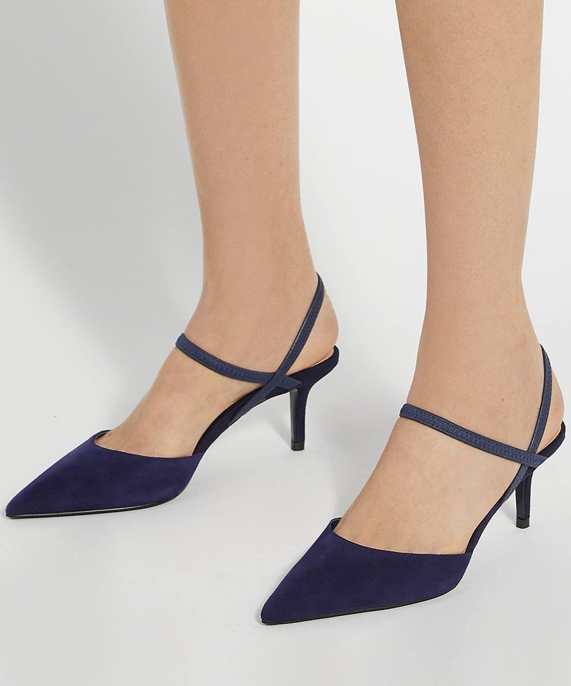 Pieds portant des escarpins slingback bleu marine à bout pointu avec de fines brides croisées et des talons aiguilles de hauteur moyenne sur fond clair.