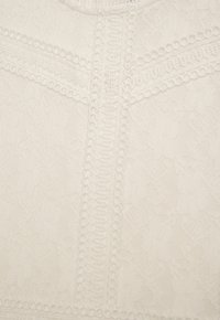 Weißer Spitzenstoff mit filigranem Blumenmuster, versehen mit erhabenen Zierlinien und runden Akzenten entlang der Nähte. Glatte Textur.