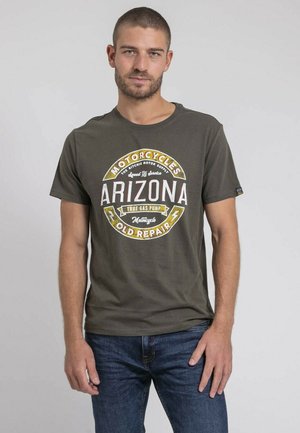 T-shirt en coton vert avec un graphique circulaire affichant "Arizona" et un texte sur le thème de la moto en blanc, jaune et rouge. Manches courtes.