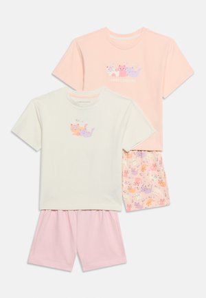 Dos conjuntos de pijama para niños con mangas cortas y pantalones cortos; uno melocotón con gatos y "Sweet Dreams", otro crema con gatos dormidos y pantalones cortos rosas.