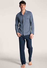 Navyblauw geruit pyjamashirt met lange mouwen en borstzak, gecombineerd met effen navy broeken, met een ontspannen pasvorm en zachte stof.