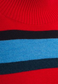 Tissu tricoté rayé rouge et bleu avec texture côtelée ; présente des rayures horizontales noires et bleu clair. Vue en gros plan mettant en évidence le détail du tissage.