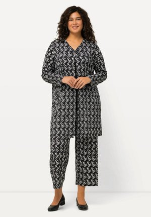 Zwart-wit gestreept outfit met een lange knoopjesblouse en bijpassende broek. Het materiaal heeft een gladde textuur en een relaxte pasvorm.