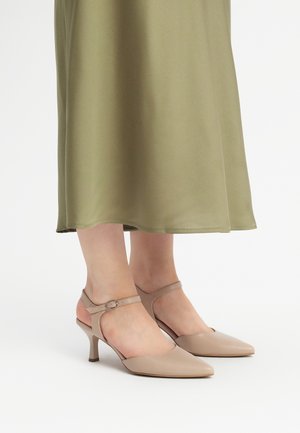 Beige slingback-korkokengät, joissa on terävä kärki, ohut nilkkavyö ja 5 cm:n korko, yhdistettynä polven mittaiseen oliivinvihreään hameeseen.