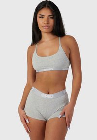 Sivi pamučni bralette i matching kratke hlačice s mekom teksturom. Pojas sadrži svijetlosivu traku s logotipom. Jednostavan, čist dizajn s podesivim trakama.