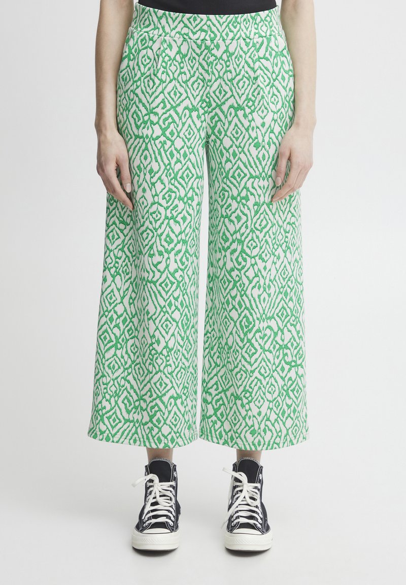 Pantalons larges en vert et blanc avec un motif géométrique complexe. Fabriqués en tissu léger, dotés de poches latérales et d'une ceinture lisse.