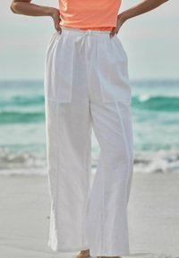 Pantaloni bianchi in lino con una vestibilità morbida, dotati di vita regolabile con cordino e due grandi tasche anteriori. Tessuto morbido e leggero.