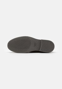Gray rubber sole with textured surface featuring circular and wave patterns, designed for traction and durability.
