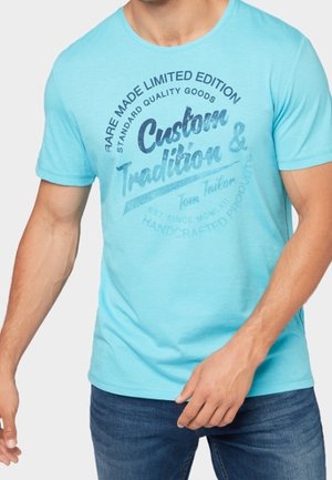 Türkisfarbenes Baumwoll-T-Shirt mit rundem Ausschnitt und kurzen Ärmeln. Der Frontdruck beinhaltet die Designelemente "Custom & Tradition" und "Tom Tailor".