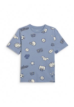 Chłopiec stoi w niebieskim t-shircie w sportowym stylu i szarych spodniach dresowych, w białych trampkach na jednolitym szarym tle.