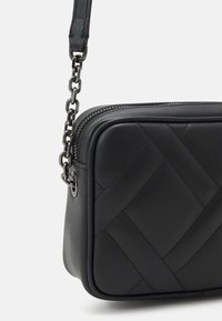 Czarna skórzana torebka na ramię z pikowanym wzorem, w kształcie prostokąta, z paskiem na łańcuszku w srebrnym odcieniu oraz zamkiem błyskawicznym. Gładka tekstura i elegancki design.