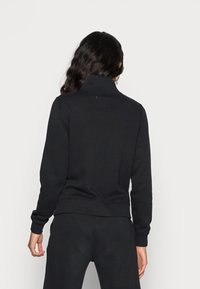 Svart sweatshirt med hög krage, ribbade manschetter och fåll. Mjuk, slät textur. Inga synliga mönster eller detaljer. Lämplig för vardagsbruk.