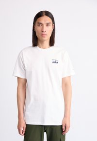 White cotton t-shirt with short sleeves; features a blue Columbia logo on the left chest. Worn with green cargo pants.