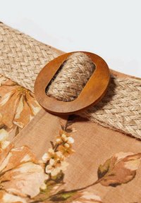 Tissu tissé avec un motif floral dans des tons chauds, comportant un grand bouton en bois et une sangle en jute texturée pour la fixation.