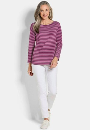 Paars gestreept shirt met lange mouwen, gecombineerd met witte slim-fit broek en witte sneakers. Het shirt heeft een ronde halslijn en is van zacht materiaal.