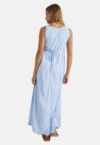 Lichtblauwe mouwloze maxi-jurk van zachte stof met een strikdetail op de rug, met een subtiel patroon en een vloeiende silhouet.