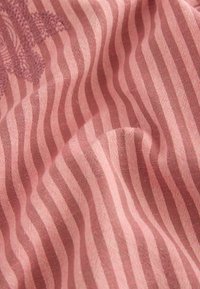 Tissu avec un textile rose texturé présentant des rayures alternées claires et foncées, mettant en valeur des fils doux et un léger éclat.