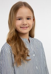 Stribet skjorte i hvid og marineblå, med kravefri design og knaplukning foran. Glat stof med subtil glans og lange ærmer.