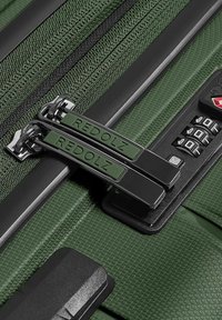 Gros plan d'une valise texturée verte avec deux fermetures éclair étiquetées Redolz et un cadenas à combinaison à trois chiffres.