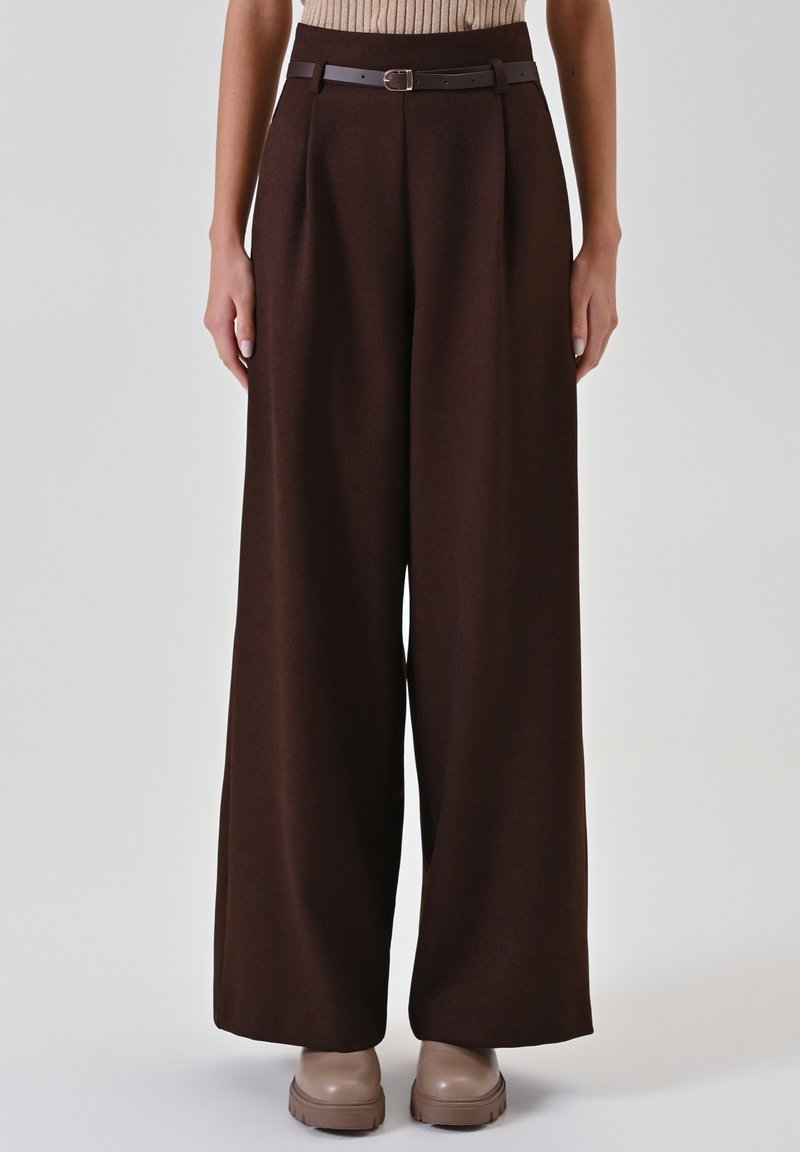 Braune Culotte-Hose mit Gürtel und Schnallendetail an der Taille, gefertigt aus strukturiertem Stoff, kombiniert mit einem gerippten Oberteil.