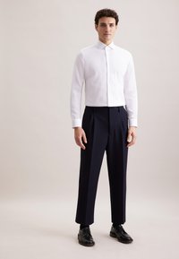 Witte button-up shirt met lange mouwen, gecombineerd met marineblauwe geplooide broeken en zwarte veterschoenen. Eenvoudig ontwerp met een klassieke pasvorm.