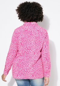 Lys pink leopardmønstret skjorte med knaplukning og lange ærmer samt spids krave. Blødt stof, afslappet pasform og en let buet søm.