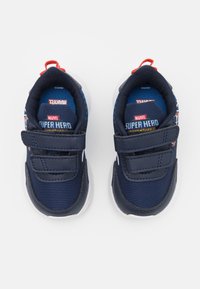Baskets bleu marine avec des bandes velcro, semelles en caoutchouc et marque Marvel. Présente un tissu texturé et des motifs de super-héros imprimés.
