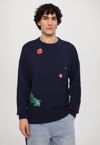 Marineblauer Strickpullover mit gestickten Erdbeer- und grünen Pflanzendesigns, mit gerippten Bündchen und Saum. Mit einem roten Akzent versehen.