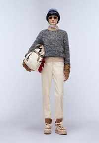 Sweter z dzianiny w wielokolorowy wzór; beżowe spodnie; brązowo-beżowe buty; kremowy plecak; niebiesko-brązowa czapka; okrągłe okulary przeciwsłoneczne.